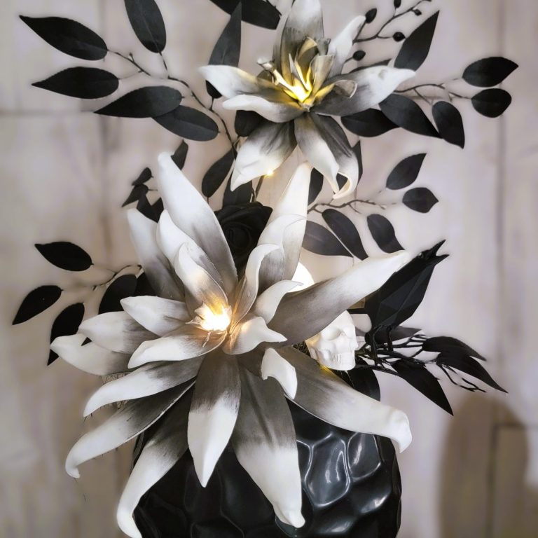 Créations fantastiques et insolites Fleurs en papier noir et blanc avec feuillage, illuminées par des lumières douces.